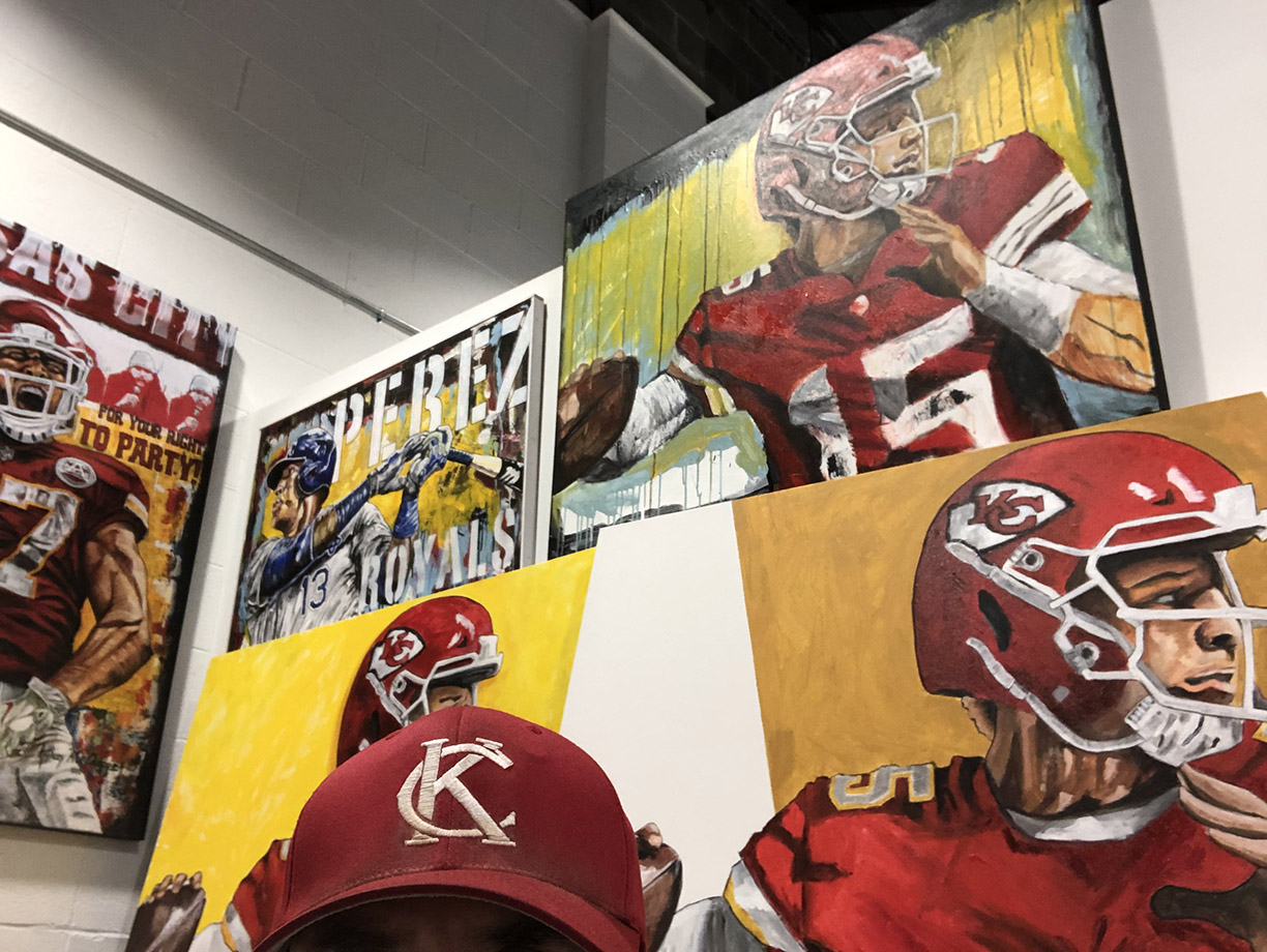 AO in his art studio with his football art paintings of Chiefs players Patrick Mahomes and Travis Kelce and a Salvador Perez baseball painting.